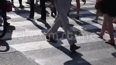 在人行横道上行走的人群的腿。人群脚的特写镜头。城市人群。